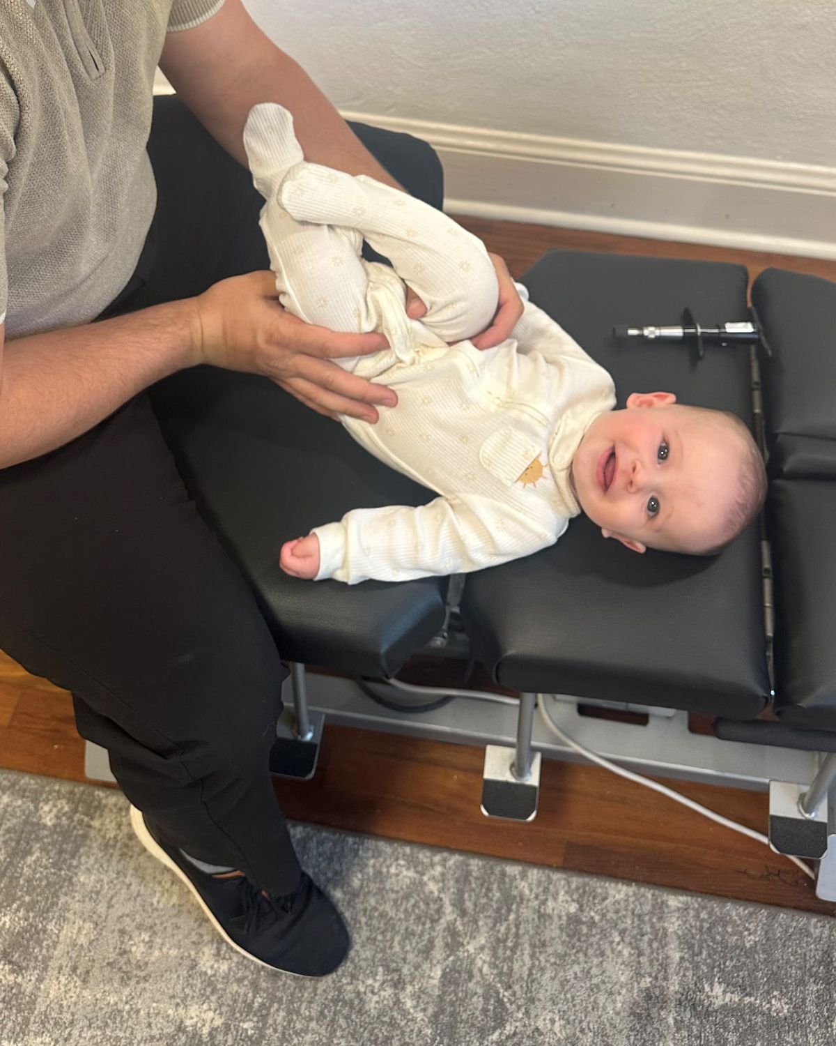 Low-force infant chiropractic care with a smiling baby on the adjusting table